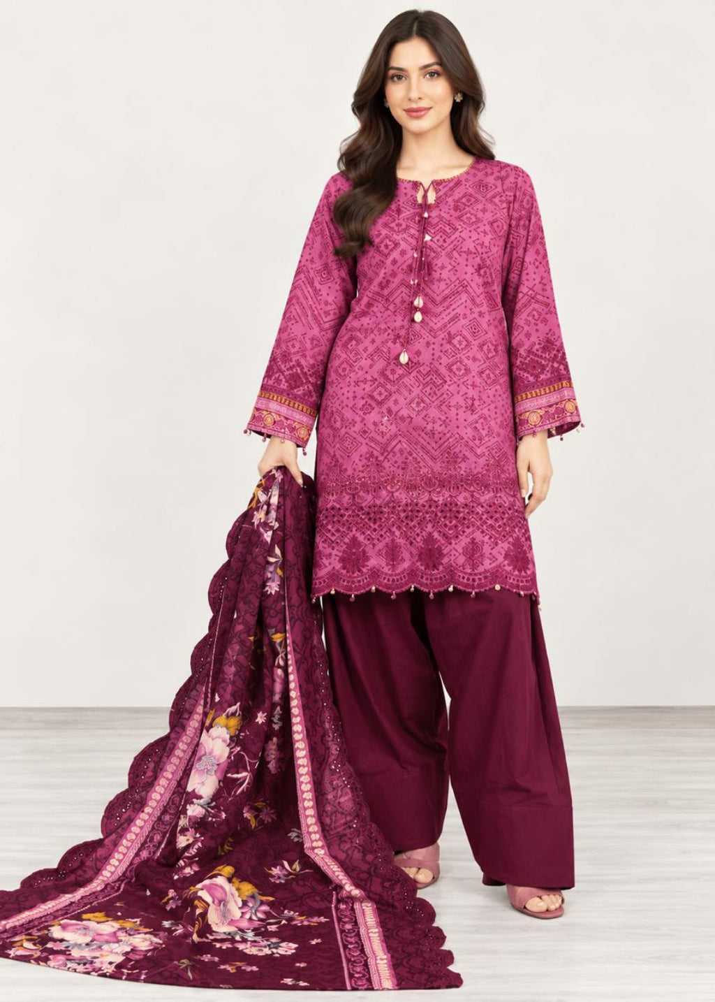 A woman modeling a three-piece traditional outfit consisting of a magenta embroidered kurta, deep maroon wide-leg pants, and a matching deep maroon floral dupatta, set against a plain light gray studio background.