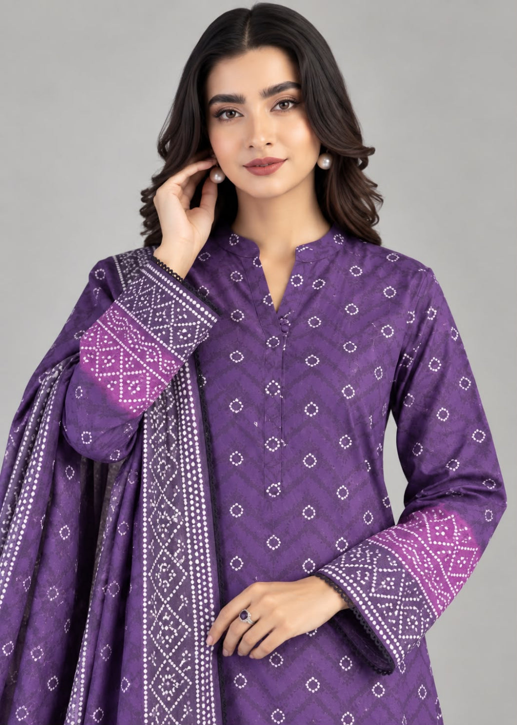 A woman modeling a purple ethnic kurta set with white printed motifs and a matching patterned dupatta against a solid gray studio background.