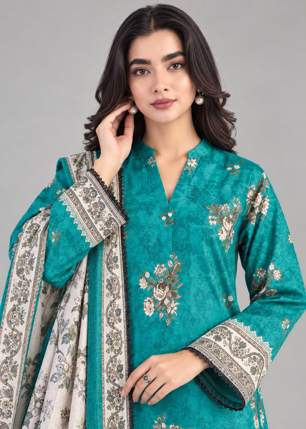 A woman modeling a teal green embroidered kurta with a matching dupatta. The kurta features intricate floral embroidery in gold, beige, and white, with patterned cuffs.
