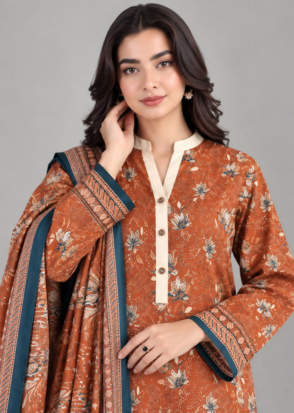 A woman modeling a rust-orange printed kurta with a cream mandarin collar and button placket, paired with a matching dupatta featuring teal and cream borders, against a solid gray studio background.
