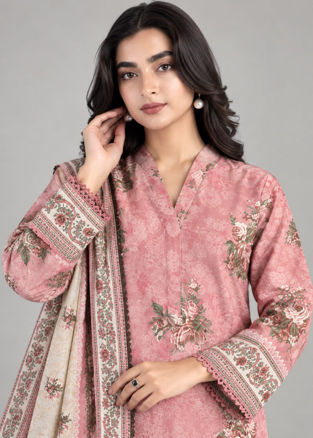 A woman modeling a pink floral printed kurta with matching patterned dupatta against a solid gray studio background.