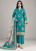 A woman modeling a traditional three-piece salwar kameez suit in teal, featuring a heavily embroidered kameez kurta with floral motifs, matching teal trousers, and a printed dupatta with a decorative border.