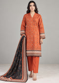 A woman modeling a traditional three-piece salwar kameez suit. The set features an orange kurta with intricate white and black geometric prints, matching orange trousers, and a black dupatta with a detailed orange and white border.