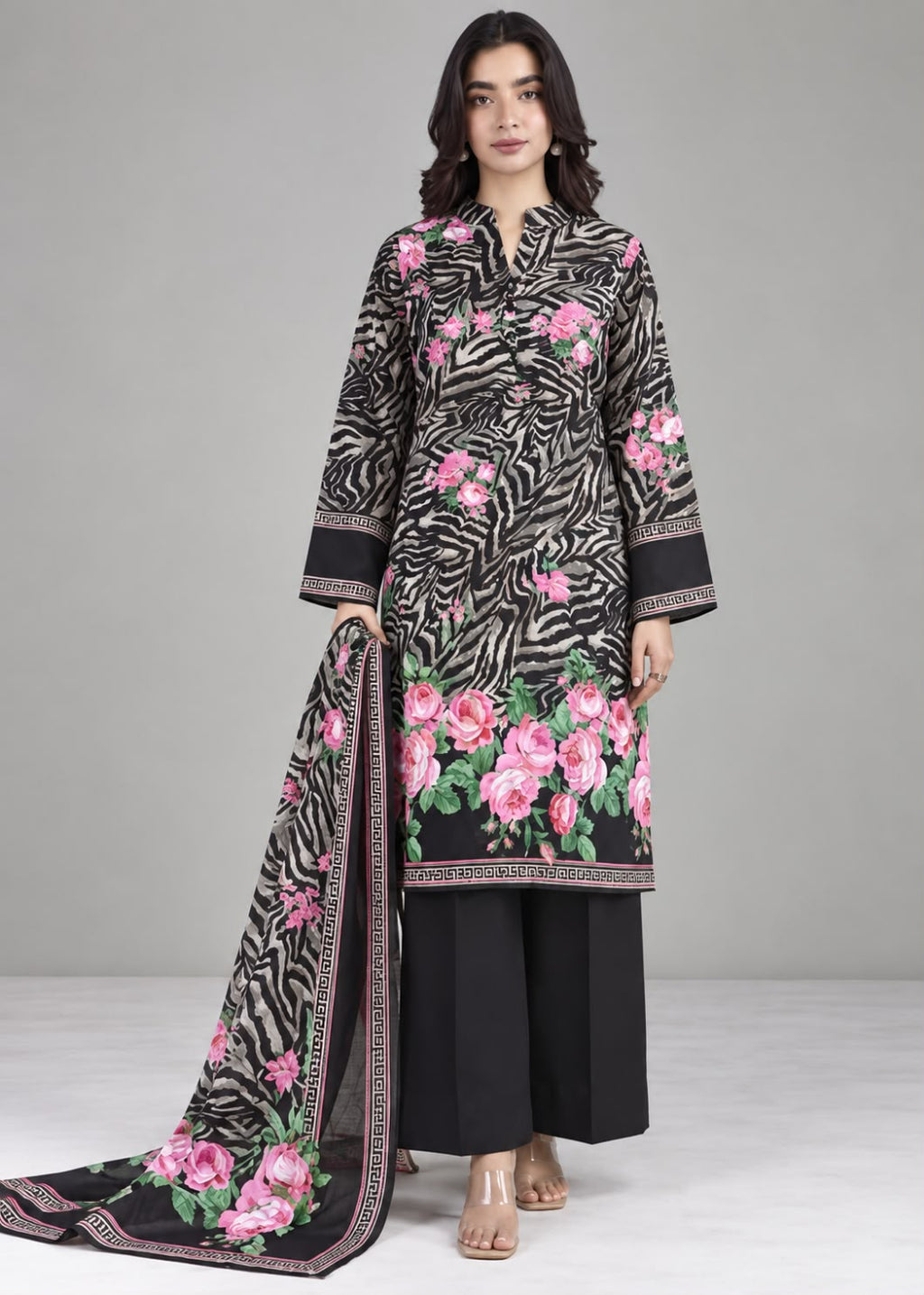 A woman models a black and white zebra-print 3-piece salwar kameez suit with pink floral embroidery and a matching dupatta, set against a neutral gray studio background.