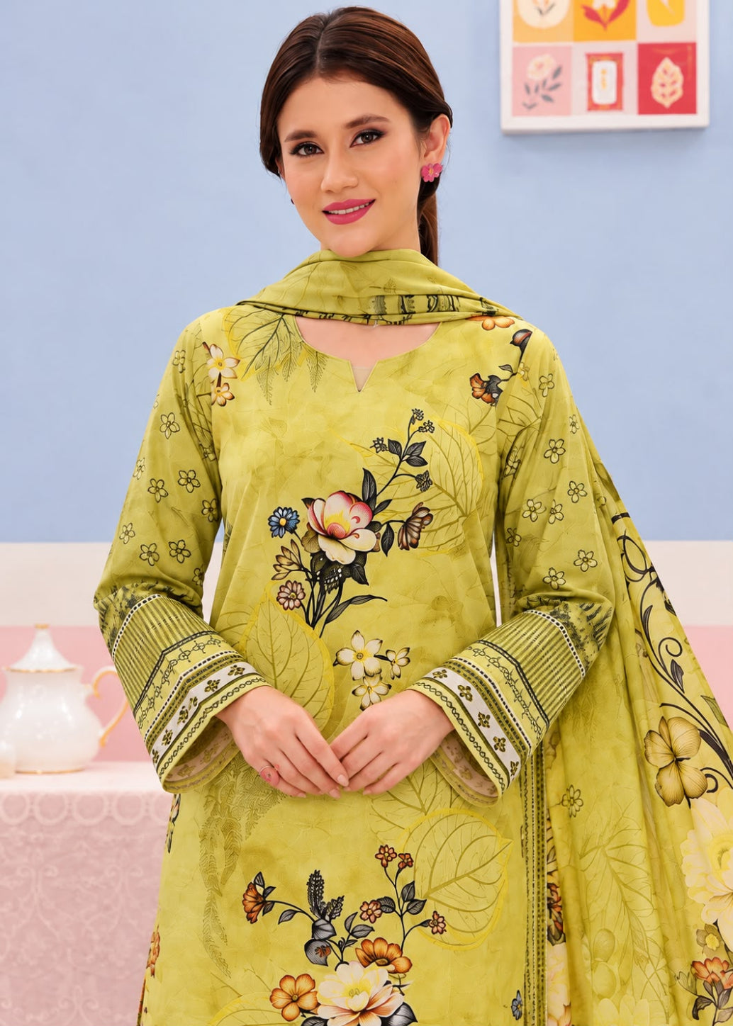 A woman modeling a traditional Indian salwar kameez set in olive green, featuring floral embroidery, printed motifs, and a matching dupatta.