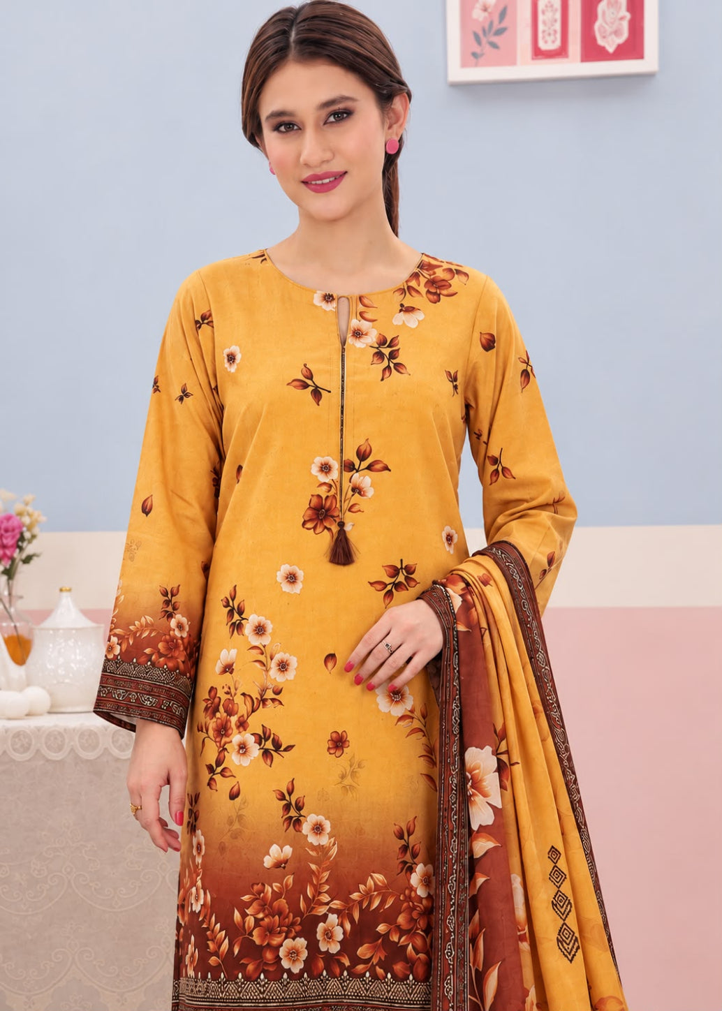 A woman modeling a mustard yellow ethnic salwar kameez suit with a brown and orange floral gradient print, featuring a matching dupatta.