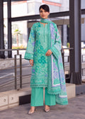 A woman models a three-piece mint green ethnic suit with floral embroidery, matching wide-leg trousers, and a coordinating dupatta in an outdoor urban setting.