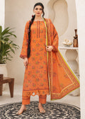 A woman models a traditional three-piece salwar kameez suit in orange, featuring floral embroidery, a matching dupatta, and cropped pants, set against a warm beige architectural background with a plant and decorative table.