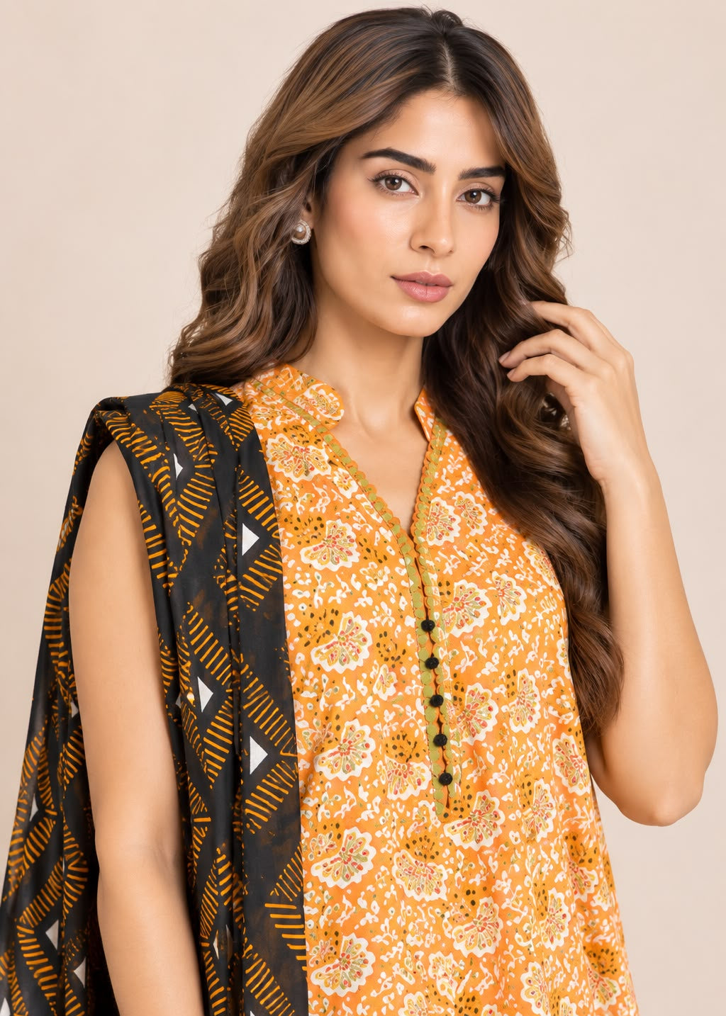 A woman modeling a sleeveless mustard yellow and orange printed kurta with a black dupatta featuring yellow and white geometric patterns, set against a solid beige background.