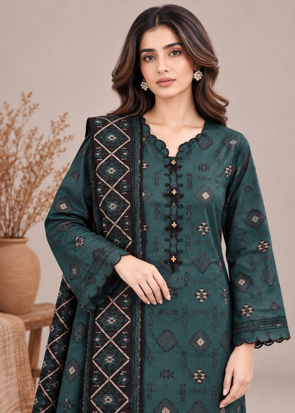 A woman modeling a dark teal green ethnic kurta with intricate black and beige geometric embroidery, paired with a matching embroidered dupatta, set against a neutral beige background.