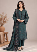 A woman models a dark teal green ethnic salwar kameez suit with matching pants and a dupatta, featuring geometric patterns and scalloped edges, set against a neutral studio background with a decorative wooden stool and vase.