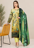 A woman models a three-piece ethnic salwar kameez suit set. The set features a mustard yellow and olive green printed kurta with blue and green floral motifs, matching solid yellow trousers, and a green striped dupatta with a floral print.