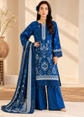 A woman models a royal blue ethnic three-piece suit set featuring a heavily embroidered kurta, matching wide-leg pants, and a coordinating dupatta with intricate white and silver patterns, set against a warm beige background.