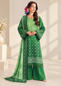 A woman models a green traditional South Asian outfit with matching printed dupatta and wide-leg pants in a bright, modern studio setting.