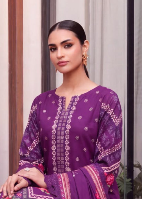 A woman modeling a purple traditional outfit with floral embroidery and printed borders, shown in a split view: a seated full-body pose on the left and a close-up portrait on the right. The setting has striped brown and beige walls and a window.
