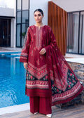 A woman models a three-piece traditional South Asian outfit consisting of a deep red embroidered kurta, matching trousers, and a sheer red dupatta with a black border and floral print, set against a modern poolside background.
