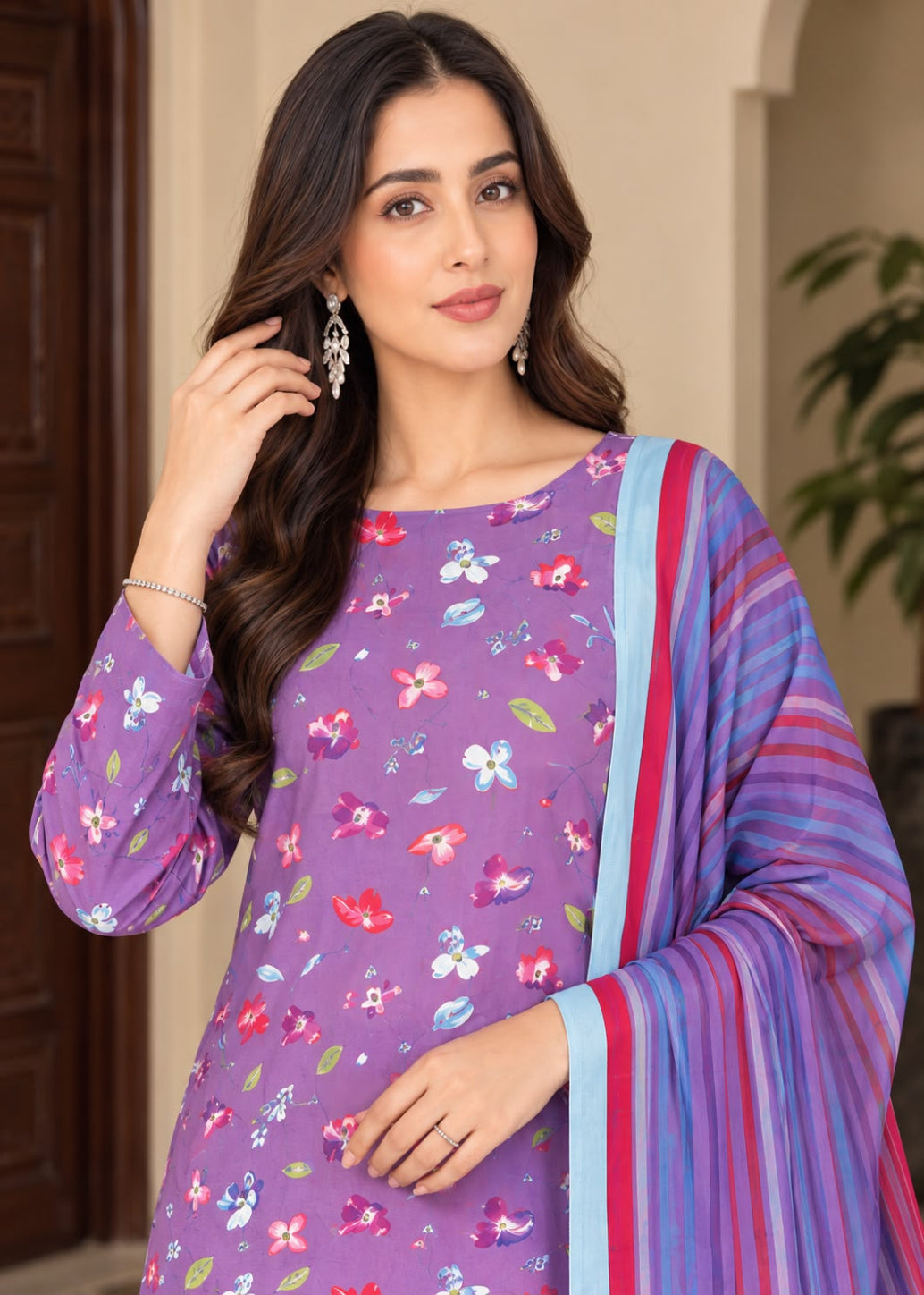 A woman modeling a purple floral printed kurta with a striped blue, purple, and red dupatta, set against an indoor architectural background.