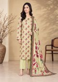 A woman models a three-piece Indian salwar kameez suit set. The set features a light sage green kurta and trousers with a vibrant magenta and green floral print, paired with a matching printed dupatta.