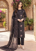 A woman models a black three-piece ethnic suit with floral embroidery, featuring a long-sleeve kurta, black trousers, and a matching sheer dupatta, set against an ornate courtyard background.