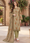 A woman models a traditional three-piece salwar kameez suit set in an outdoor courtyard setting. The set features a beige kurta with orange floral patterns, olive green pants, and a matching beige dupatta with intricate border detailing.