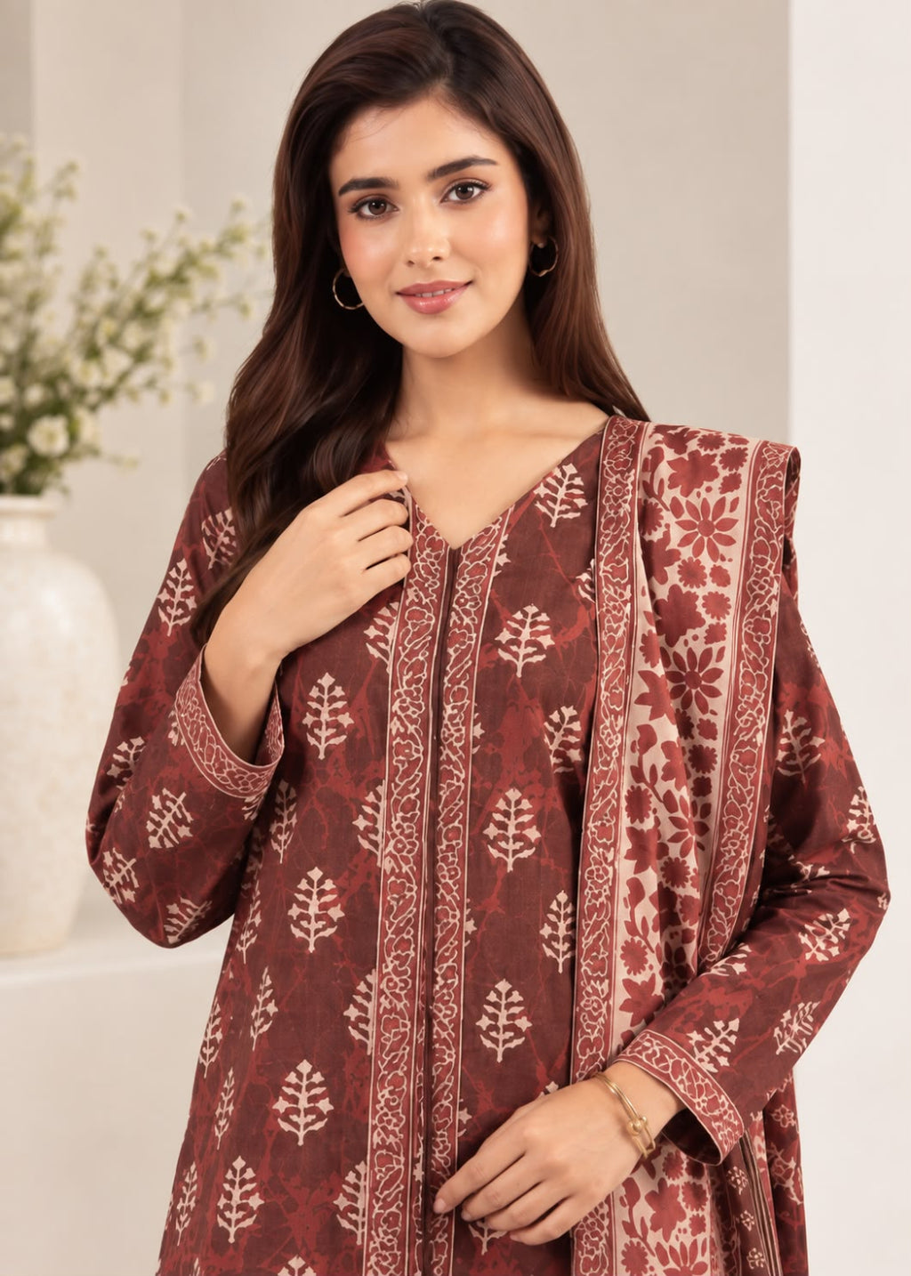 A woman wearing a rust-brown and beige block-printed kurta with a matching dupatta, shown in a clean indoor setting.