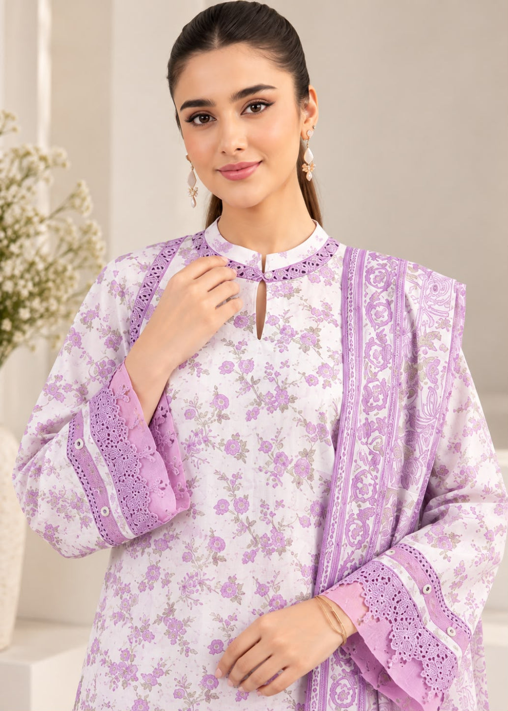 A woman modeling a traditional South Asian outfit featuring a white kurta with a light purple floral print, lavender embroidered borders, and matching embroidered cuffs, paired with a matching lavender dupatta.