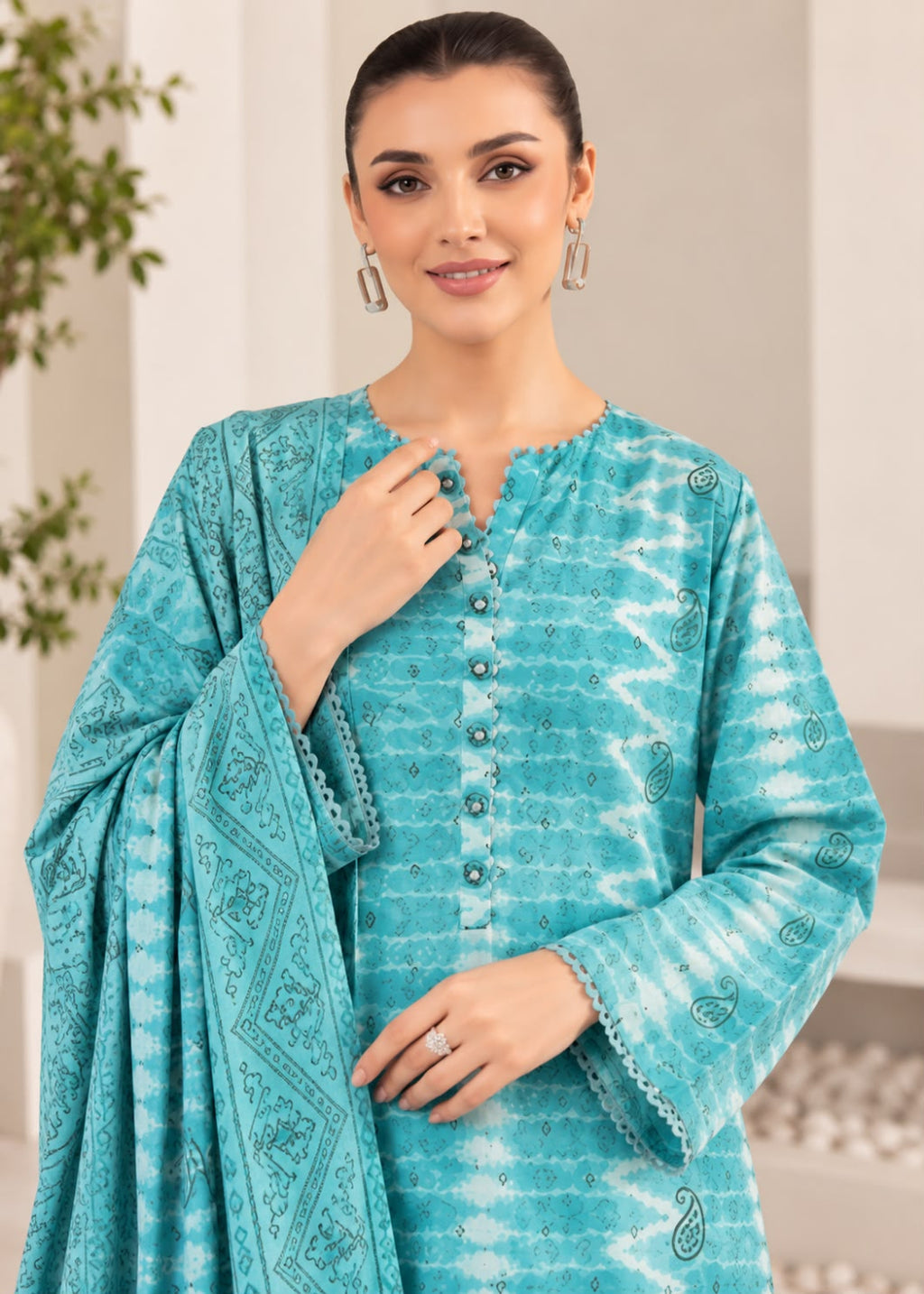 A woman modeling a turquoise blue and white tie-dye ethnic three-piece suit with a matching dupatta, featuring a buttoned V-neck tunic and paisley patterns.