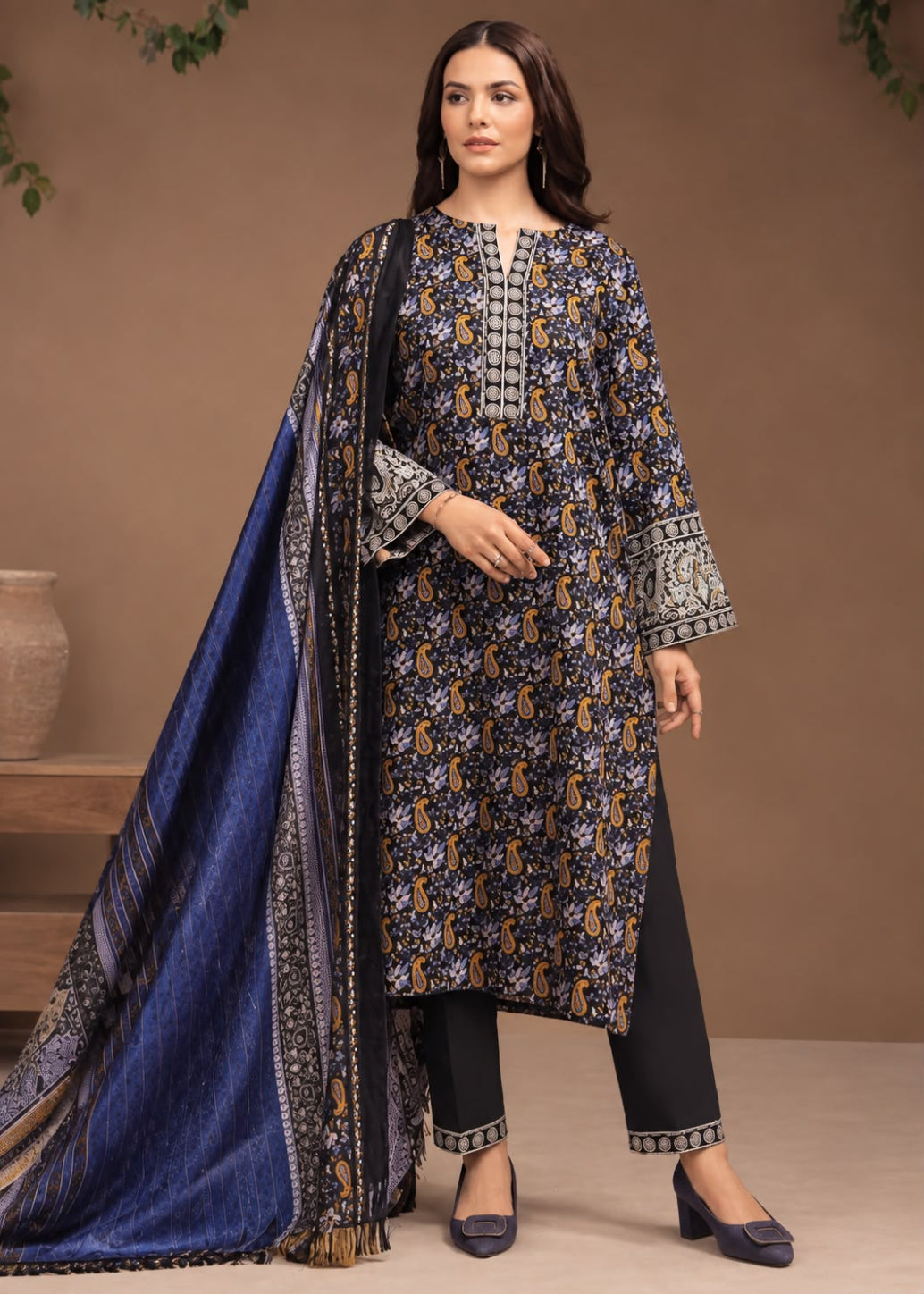A woman models a traditional three-piece salwar kameez suit. The set includes a navy blue kurta with intricate gold and white floral patterns, black trousers with gold patterned hem borders, and a matching navy blue dupatta with gold and white borders.