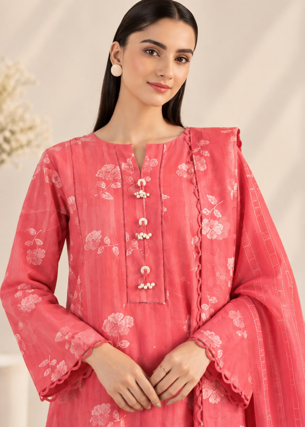 A woman modeling a pink floral printed kurta with a matching dupatta, featuring a split neckline, decorative front buttons, and scalloped cuffs.