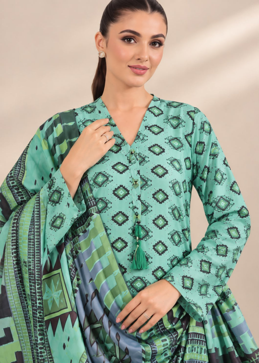 A woman modeling a mint green and black printed traditional outfit with a matching patterned dupatta, set against a soft beige background.