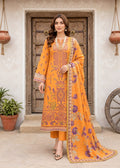 A woman models a traditional Indian salwar kameez suit in a warm orange-yellow color with purple floral prints and intricate embroidery. The set includes a long kurta, matching trousers, and a dupatta, styled with a gold necklace and leopard print heels, set against a rustic wooden door background.