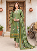 A woman models a three-piece olive green ethnic suit with floral embroidery and a matching dupatta, standing in front of a rustic wooden door.