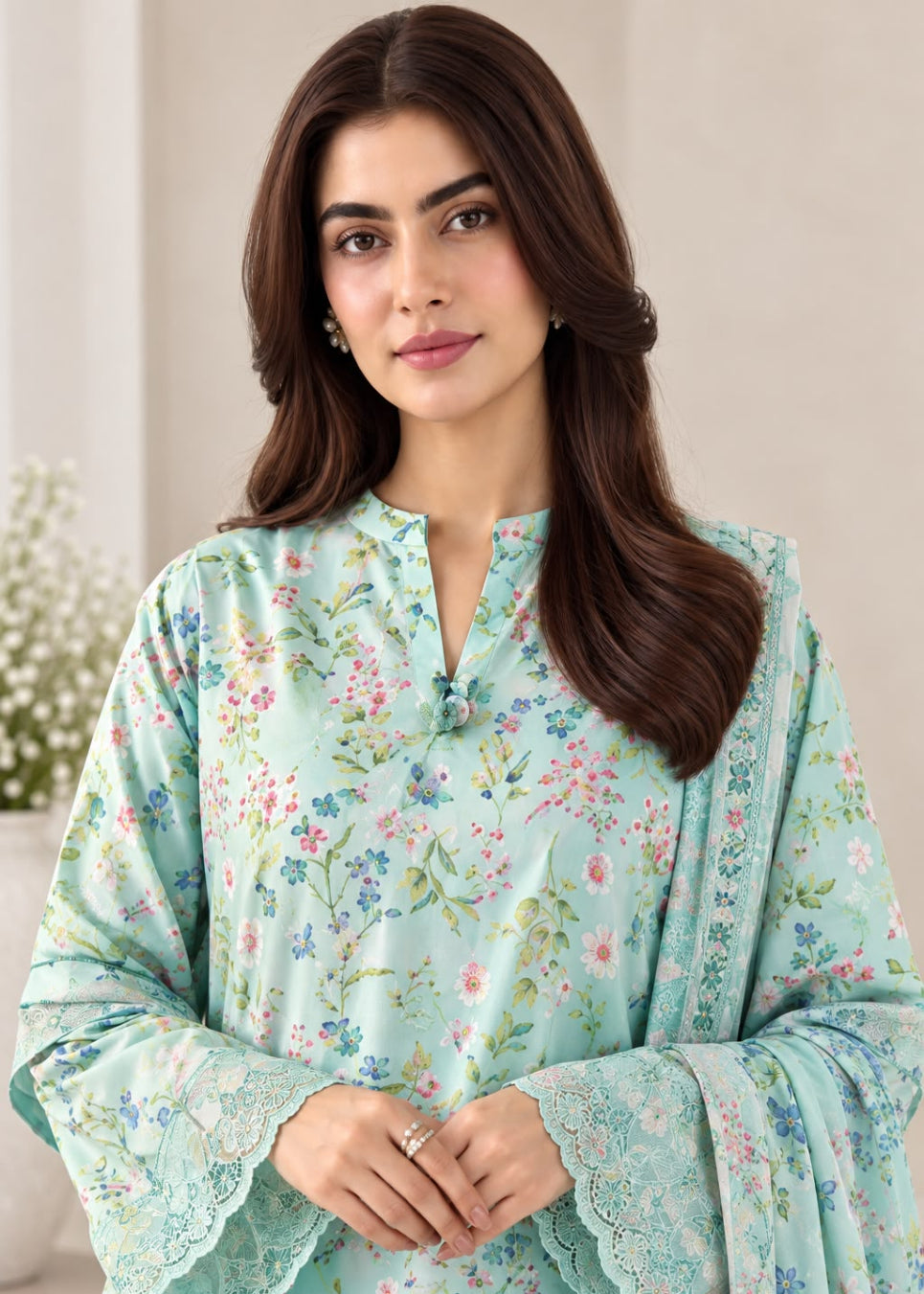 A woman wearing a mint green floral printed kurta with long bell sleeves and lace trim, standing against a soft beige background.
