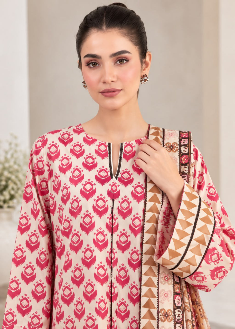 A woman modeling a cream-colored traditional kurta with a vibrant pink and brown geometric ikat pattern, paired with a matching patterned dupatta.