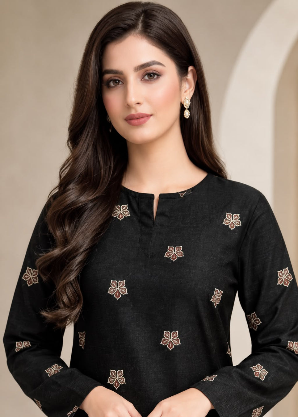 A woman wearing a black long-sleeve kurta with small beige and brown floral embroidery, posed against a neutral beige background.