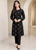 A woman modeling a black long-sleeve kurta with small beige floral motifs and matching black pants in a neutral indoor setting with arches.