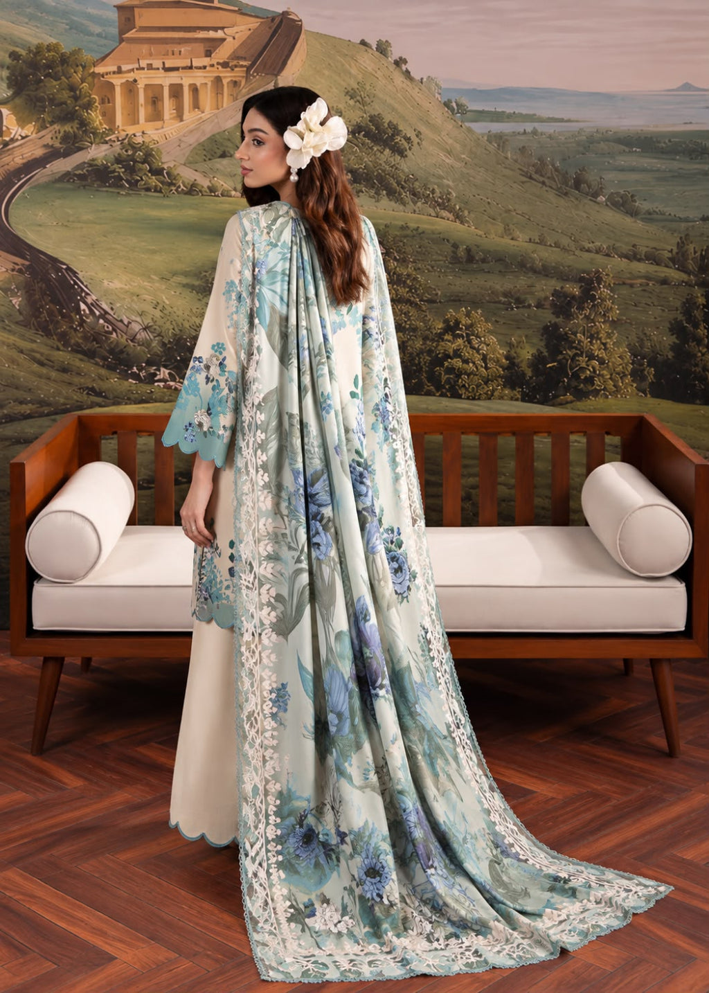 A woman models a traditional South Asian outfit consisting of a cream-colored kurta and flared pants with a matching printed dupatta. The dupatta features a light blue and white floral pattern with intricate lace borders.
