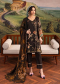 A woman models a three-piece black floral salwar suit set with a matching dupatta, standing in front of a wooden bench and a scenic landscape mural.