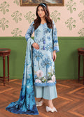 A woman models a light blue three-piece traditional South Asian outfit with floral embroidery, a matching dupatta, and wide-leg pants in a decorated room with patterned wallpaper and wooden floors.