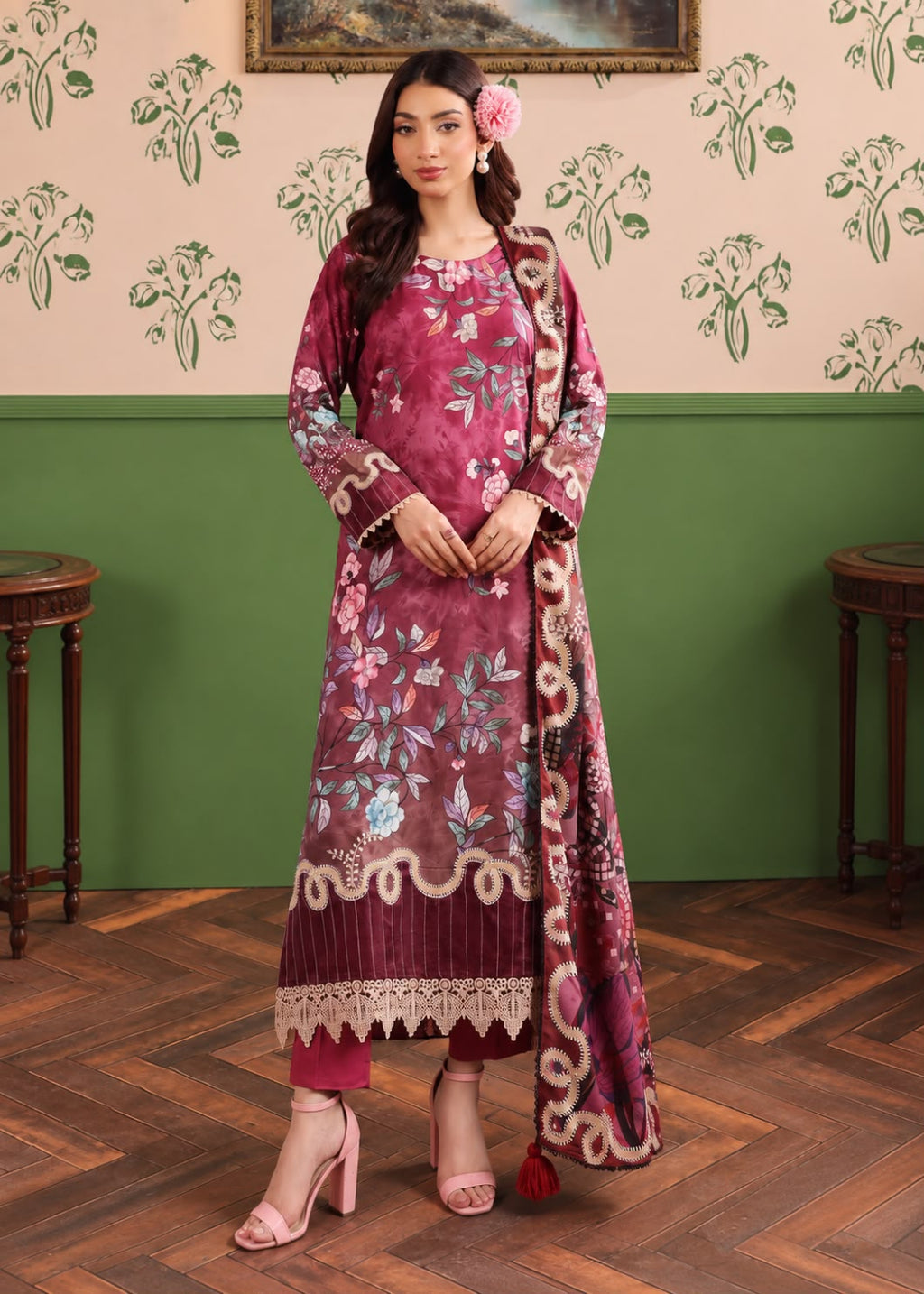 A woman models a traditional Indian salwar kameez suit in a dusty magenta color with floral embroidery and a matching dupatta, set against a green and beige patterned wall and wooden floor.