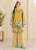 A woman modeling a mustard yellow three-piece kurta set with blue and white floral prints on the tunic, blue chevron sleeve accents, matching wide-leg pants with a yellow and white chevron pattern, a matching headscarf, and turquoise platform sandals.