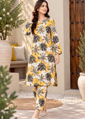 A woman modeling a yellow and black tropical leaf print kurta set in an outdoor patio setting with potted plants and a wooden door.