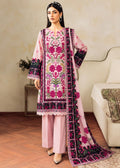 A woman models a traditional three-piece salwar kameez suit in light pink with vibrant magenta, green, and black floral embroidery on the tunic and dupatta, paired with matching pink palazzo pants in a styled indoor setting.