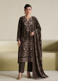 A woman models a dark brown velvet ethnic suit set featuring intricate silver and white embroidery, matching dark brown trousers, and a coordinating dupatta, set against a minimalist beige background.