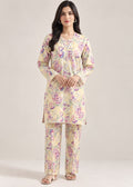 A woman modeling a two-piece Indian ethnic kurta set with matching trousers. The set features a light beige base with a vibrant floral print in purple, pink, and green.
