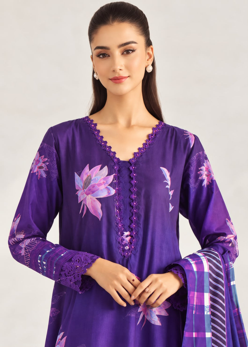 A woman modeling a purple three-piece salwar kameez suit with floral prints and a matching plaid dupatta, set against a plain light gray background.