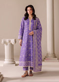 A woman modeling a traditional purple three-piece salwar kameez suit with beige/gold embroidery and a matching patterned dupatta, standing between classical columns in a beige studio setting.