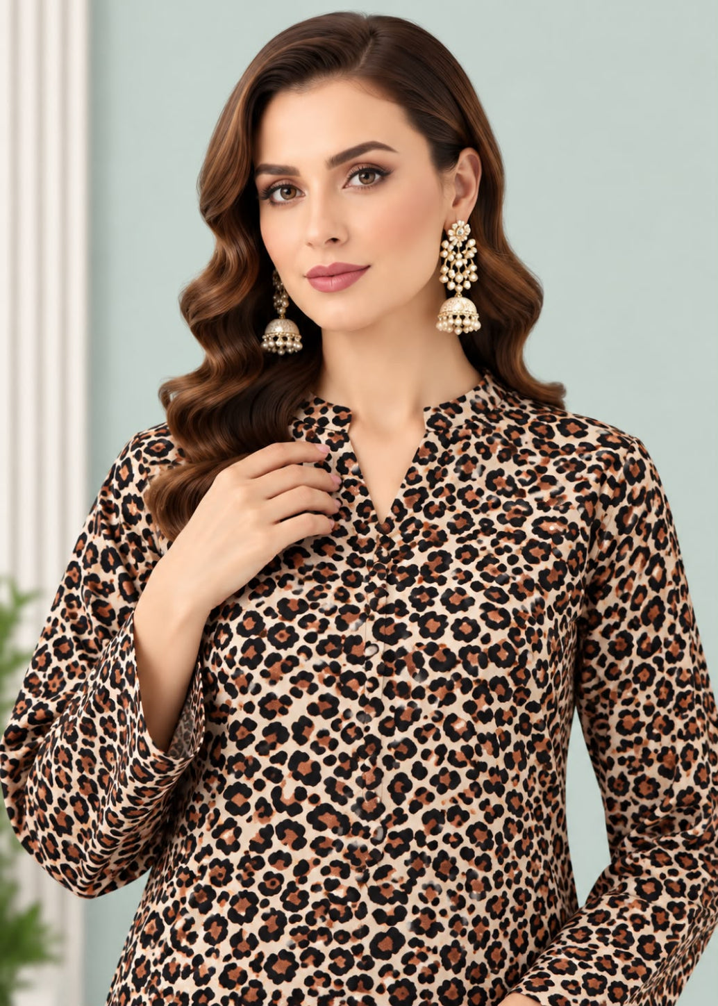 A woman wearing a beige leopard print long-sleeve blouse with a split neckline, paired with statement earrings, set against a soft light blue background.