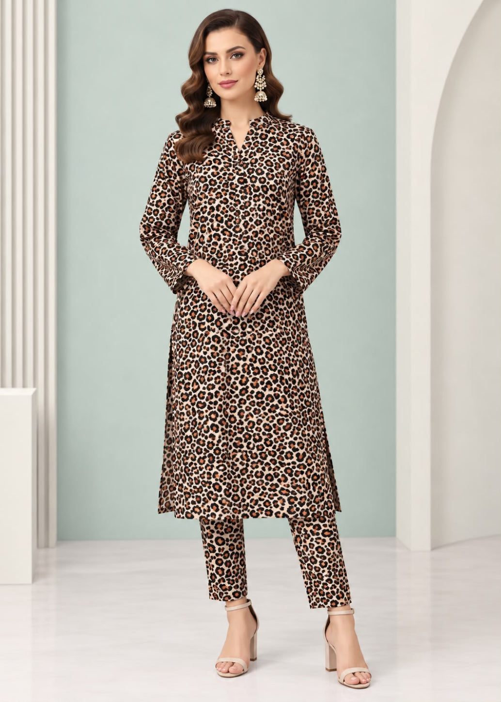 A woman modeling a brown and black leopard print kurta set with matching pants, standing in a studio with a light green and white background.