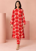 A woman modeling a red and cream floral print kurta set with matching pants, standing in a studio with pink geometric props.